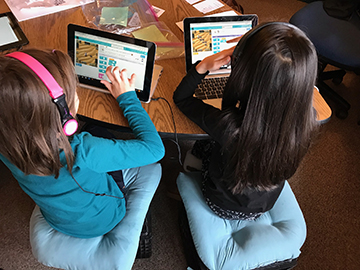 Daily attendance is important. Two students working on Chromebooks in the classroom. 